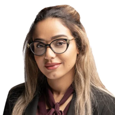 Woman with long, light brown hair wearing glasses, a black blazer, and a maroon blouse with a bow, posing against a white background.