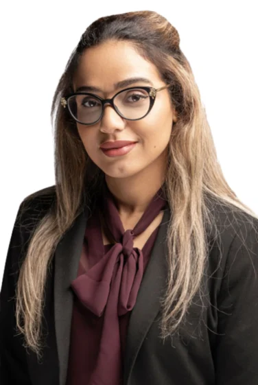 Woman with long, light brown hair wearing glasses, a black blazer, and a maroon blouse with a bow, posing against a white background.