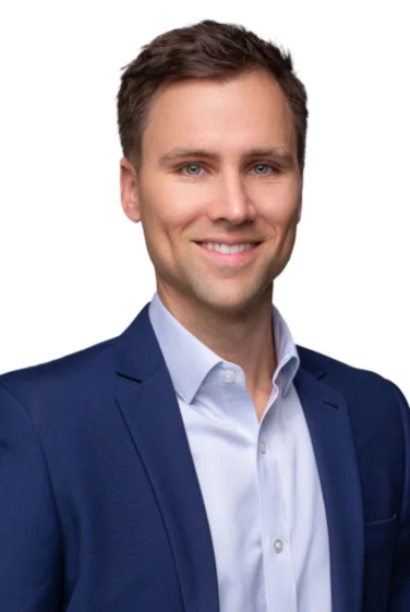 Man in a blue suit jacket and white shirt smiling at the camera against a white background.