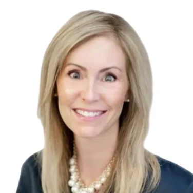Woman with straight blonde hair wearing a dark blouse and a pearl necklace, smiling at the camera against a white background.