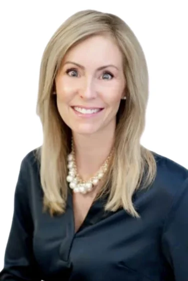 Woman with straight blonde hair wearing a dark blouse and a pearl necklace, smiling at the camera against a white background.
