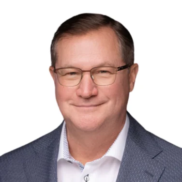 Middle-aged man wearing glasses, a white dress shirt, and a textured blue blazer, smiling slightly while facing the camera against a plain white background.