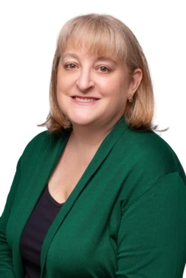 Woman with shoulder-length blonde hair, wearing a green cardigan and black top, smiling at the camera against a white background.