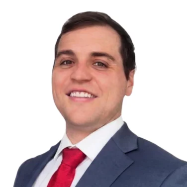 Man in a blue suit and red tie smiling, posing for a professional portrait against a white background.