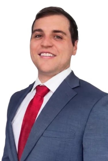 Man in a blue suit and red tie smiling, posing for a professional portrait against a white background.