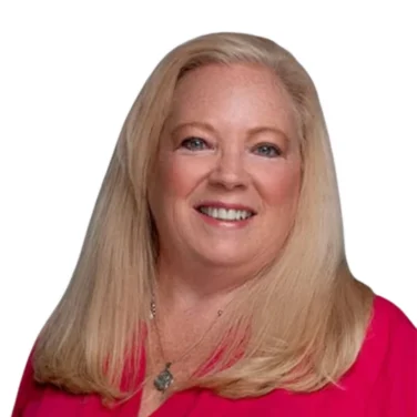A woman with long blond hair and a bright pink blouse smiles at the camera against a white background.