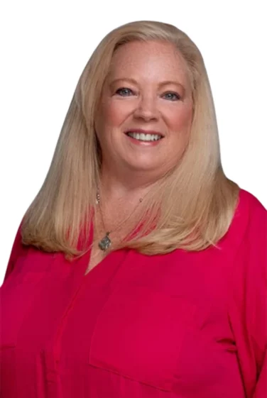 A woman with long blond hair and a bright pink blouse smiles at the camera against a white background.